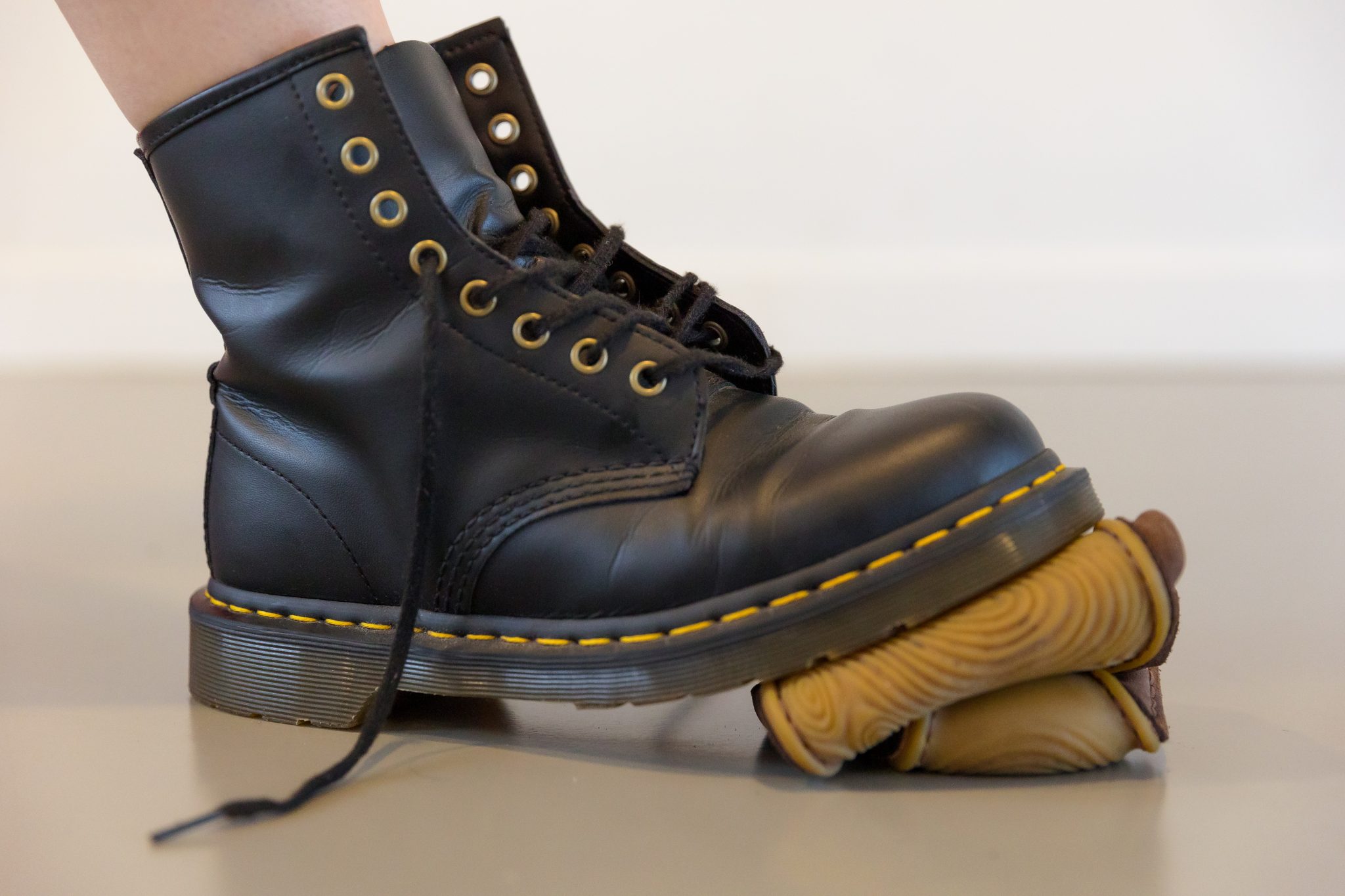 En barfodssko ligger krøllet sammen under en kraftig støvle, så man kan se, hvor fleksibel barfodsskoen er.