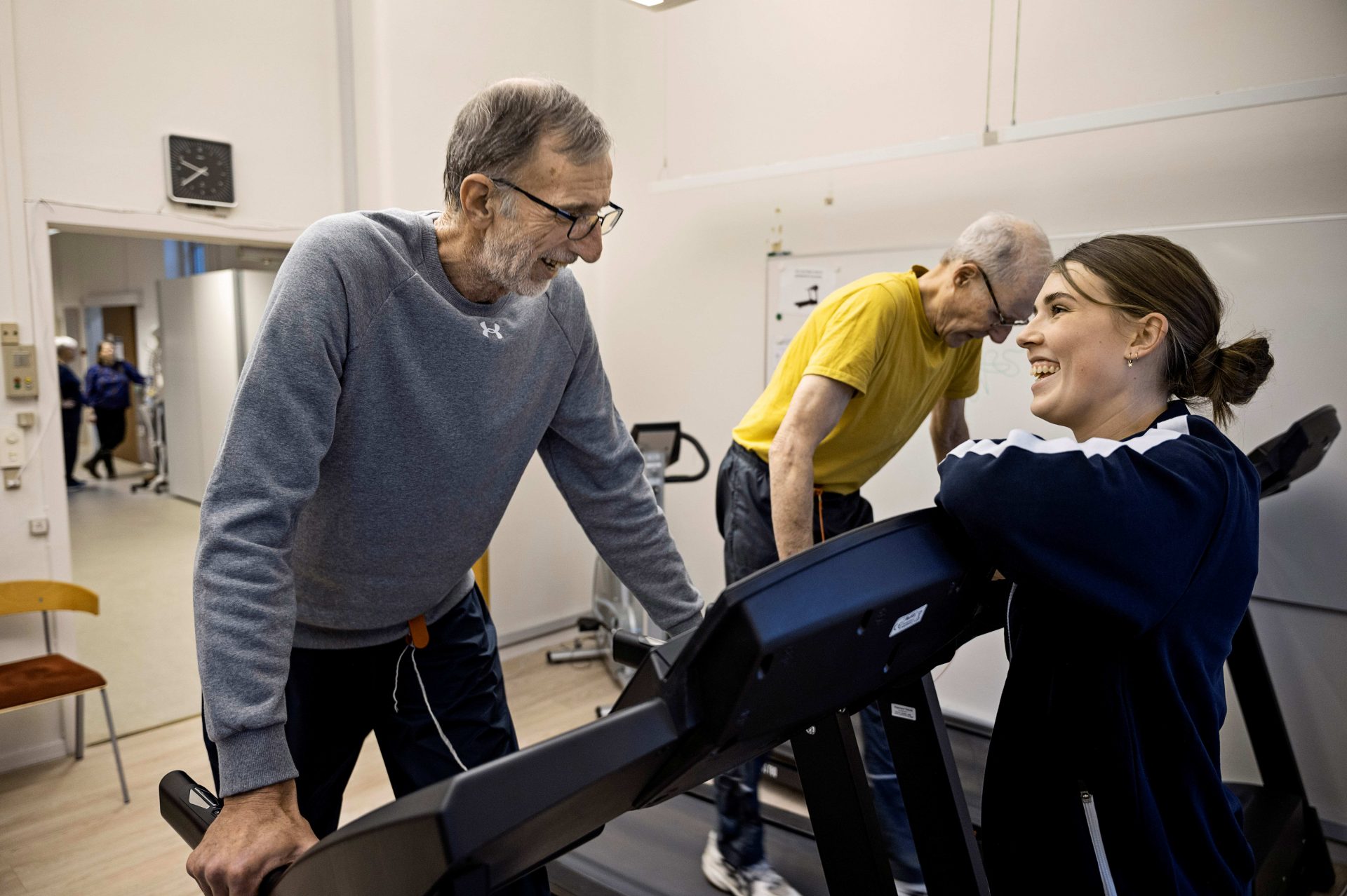 Per er i gang med at gå på løbebåndet,, mens en fysioterapeut opmuntrer ham.